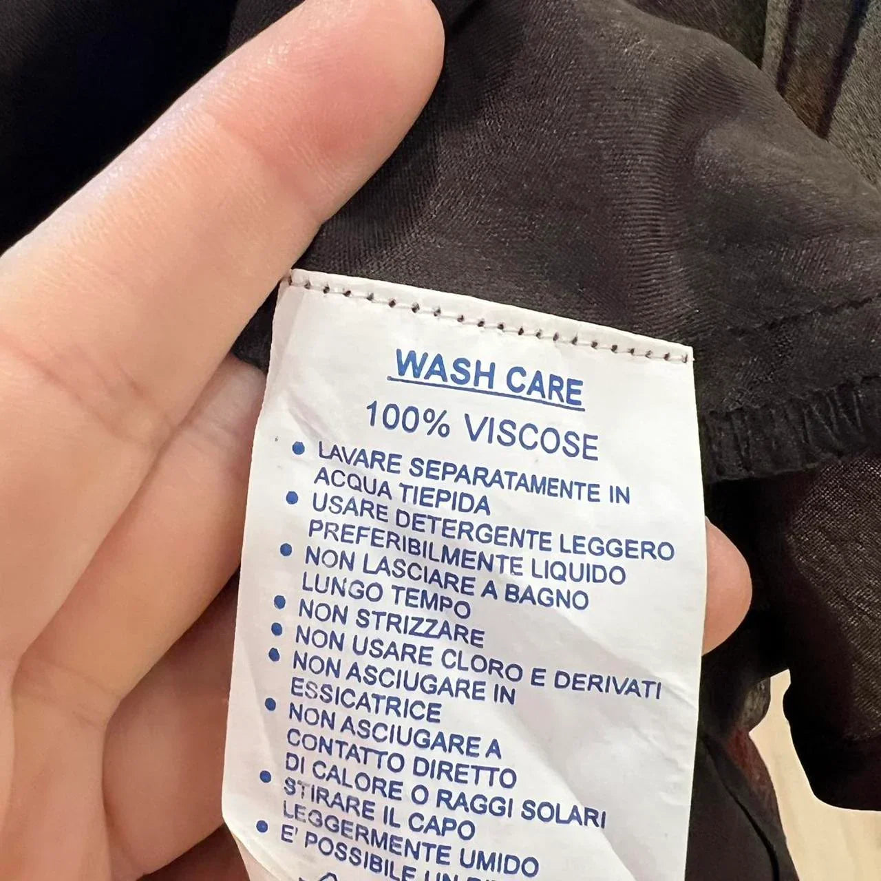 Hand holding garment with 100% viscose wash care label, sustainable fashion focus
