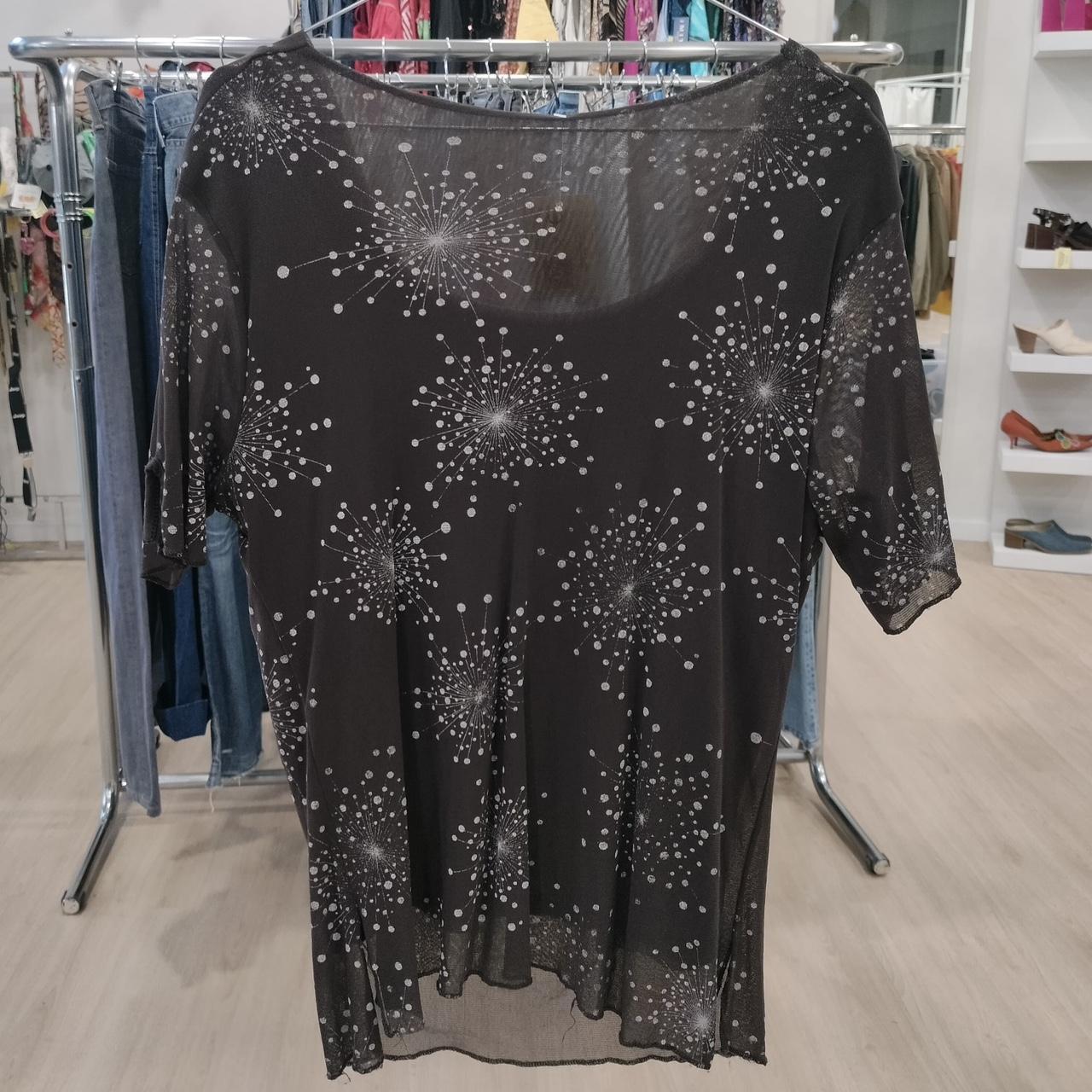Sheer black shirt with white starburst pattern, short sleeves, displayed in a fashion boutique