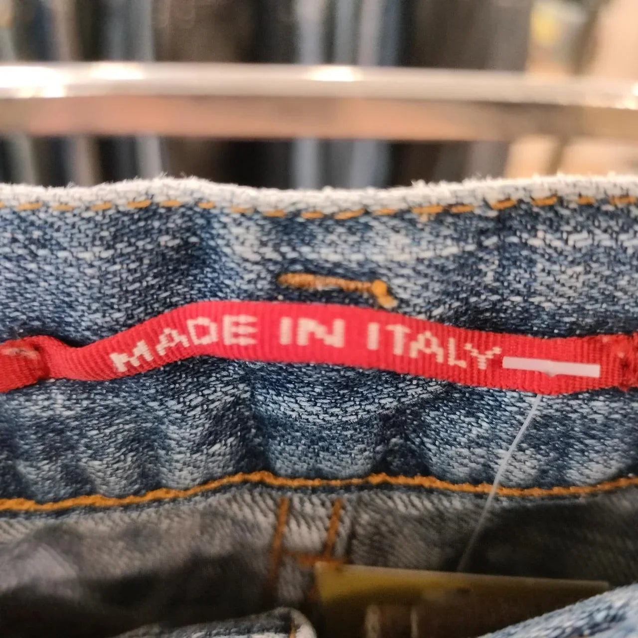 Close-up of blue denim jeans with red 'Made in Italy' label inside waistband