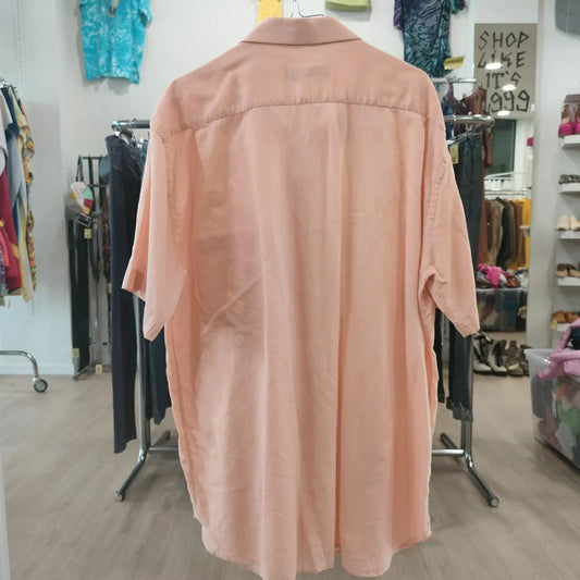 Peach short sleeve button-up shirt displayed in a second hand clothing store