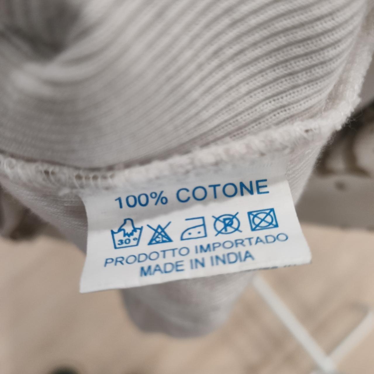 White garment care label showing 100% cotton, washing icons, and made in India text