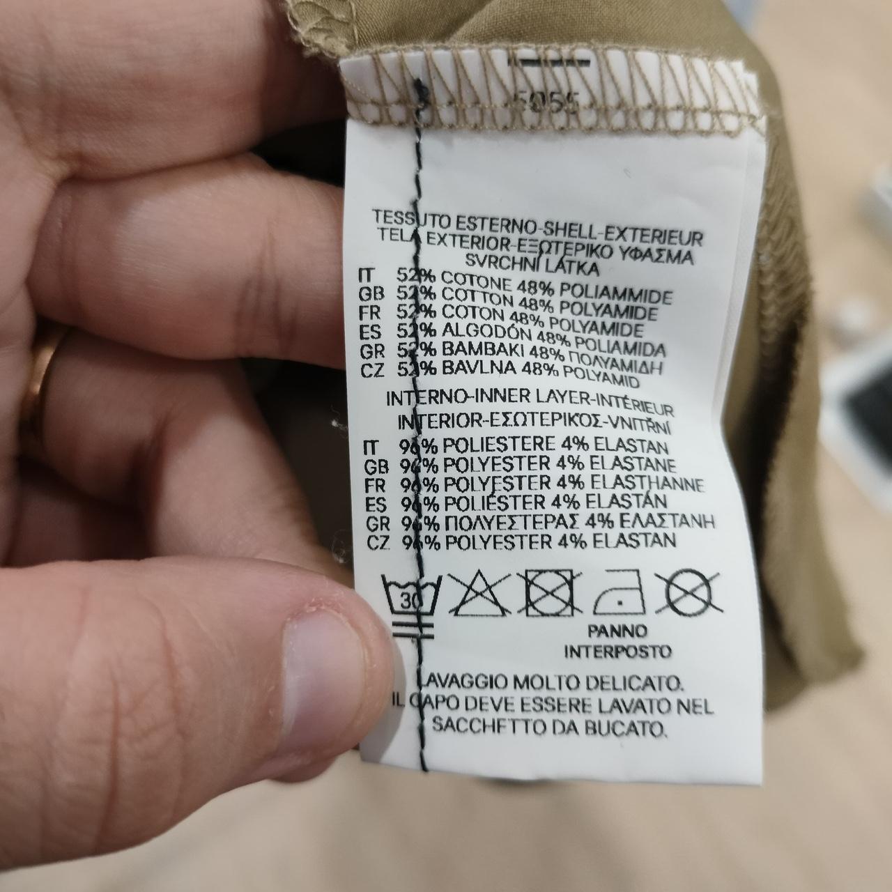 Close-up of a clothing label with text and symbols on a beige fabric background