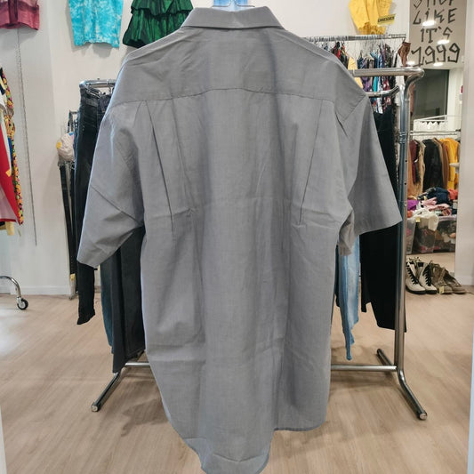 Gray shirt on a hanger in a store setting with various clothing items in the background