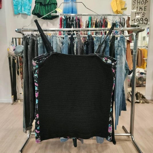 Black smocked tank top with floral side panels on hanger in a vintage clothing store