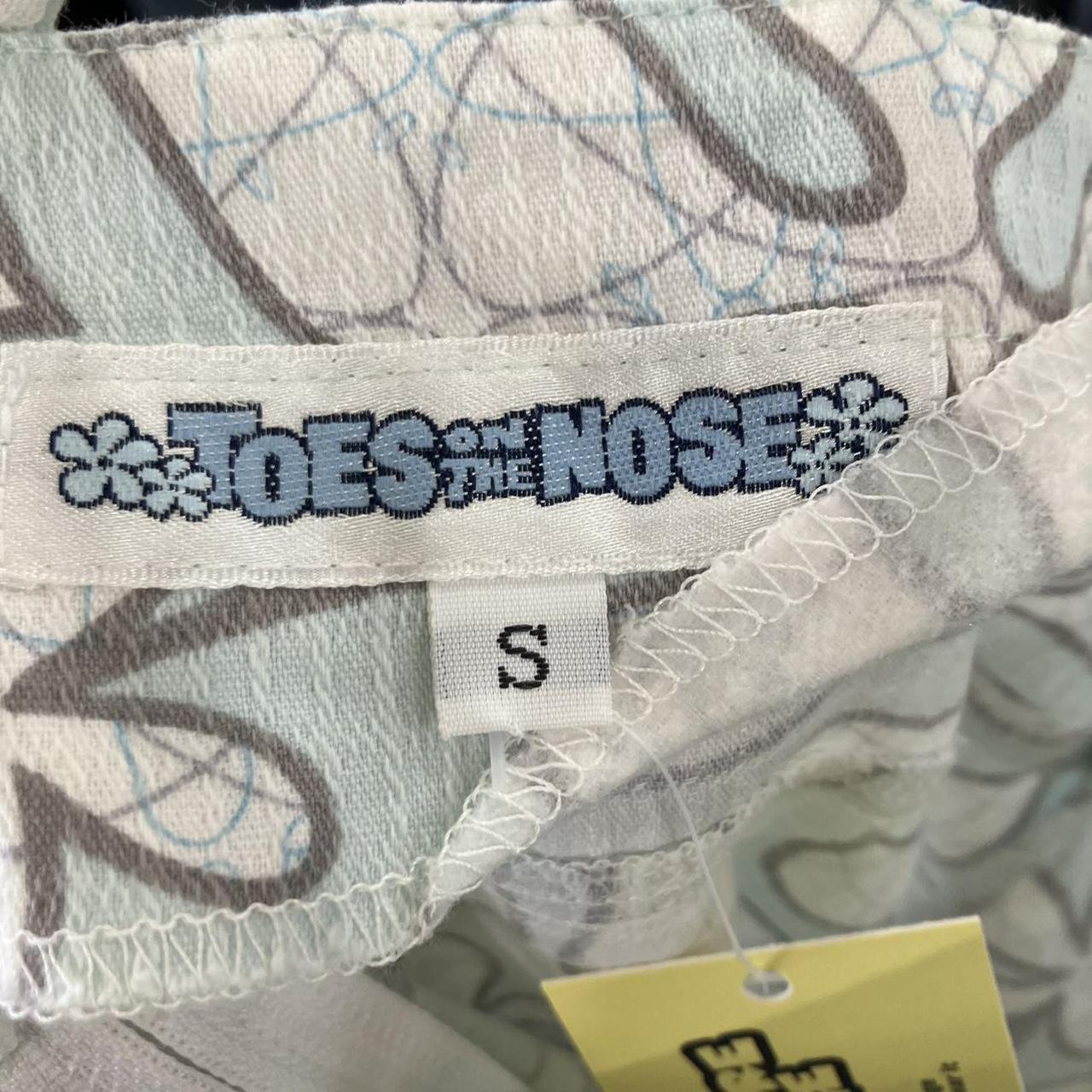 Label with 'Toes the Nose' branding on a piece of fabric