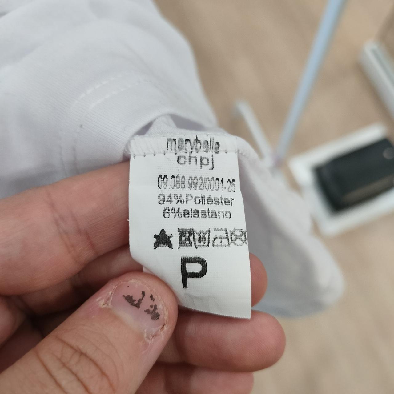 Close-up of white clothing care label showing 94% polyester, 6% elastane composition