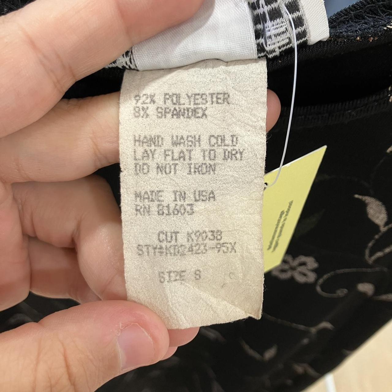 Clothing tag with care instructions and material details held by a hand