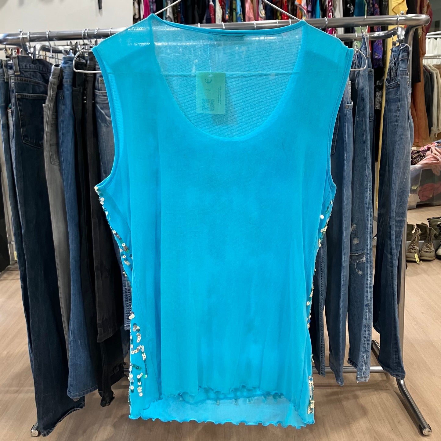 Blue sleeveless top with embellishments on a clothing rack in a store