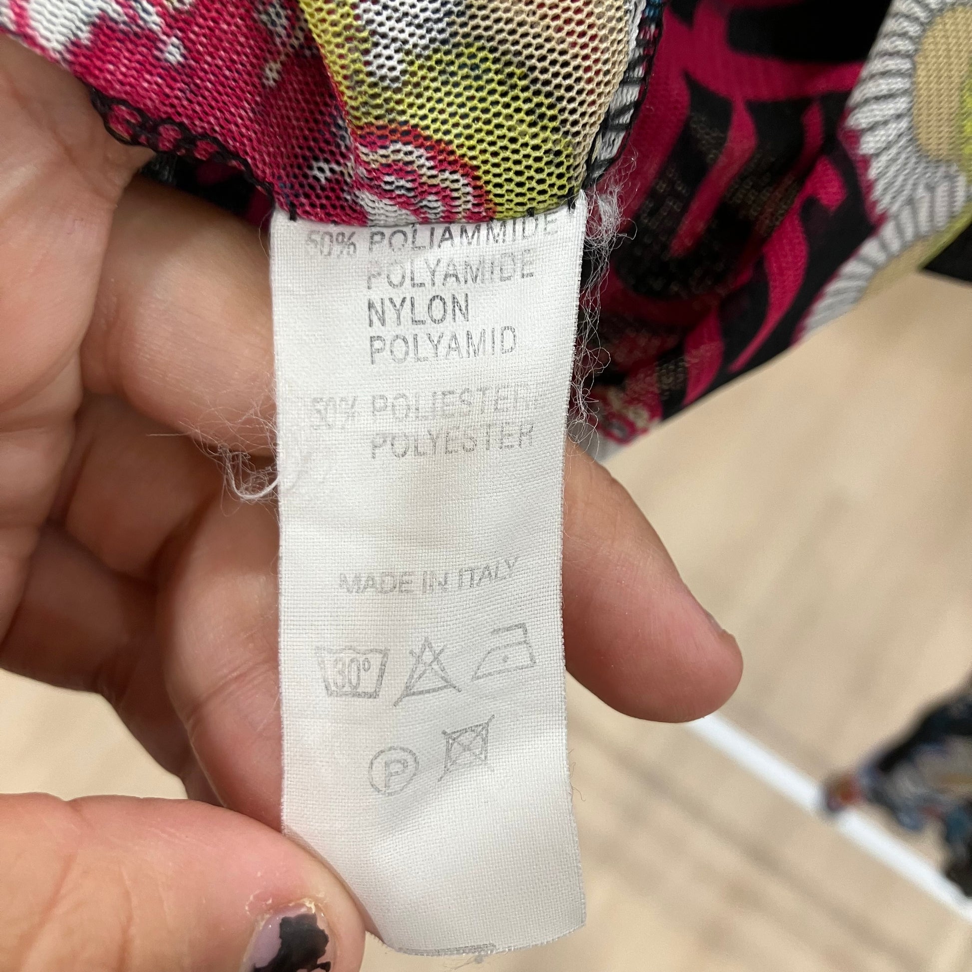 Close-up of a fabric label with material information held by a hand