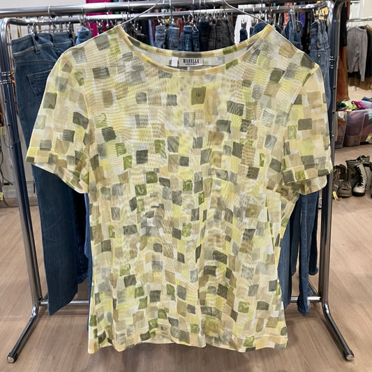 Green and yellow patterned shirt on a clothing rack with jeans in the background