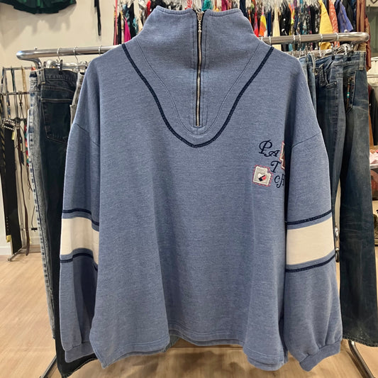 Blue pullover with a zipper on a rack in a store setting