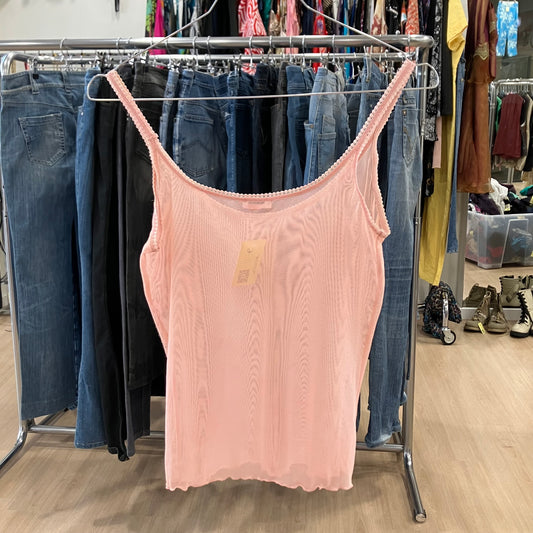 Light pink sleeveless tank top on hanger in second hand clothing store with jeans display