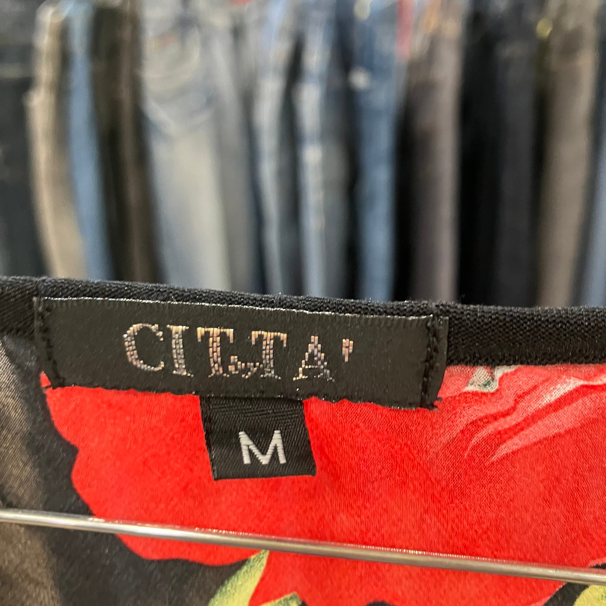 Close-up of a label on a garment with 'CITTA' branding and size 'M'