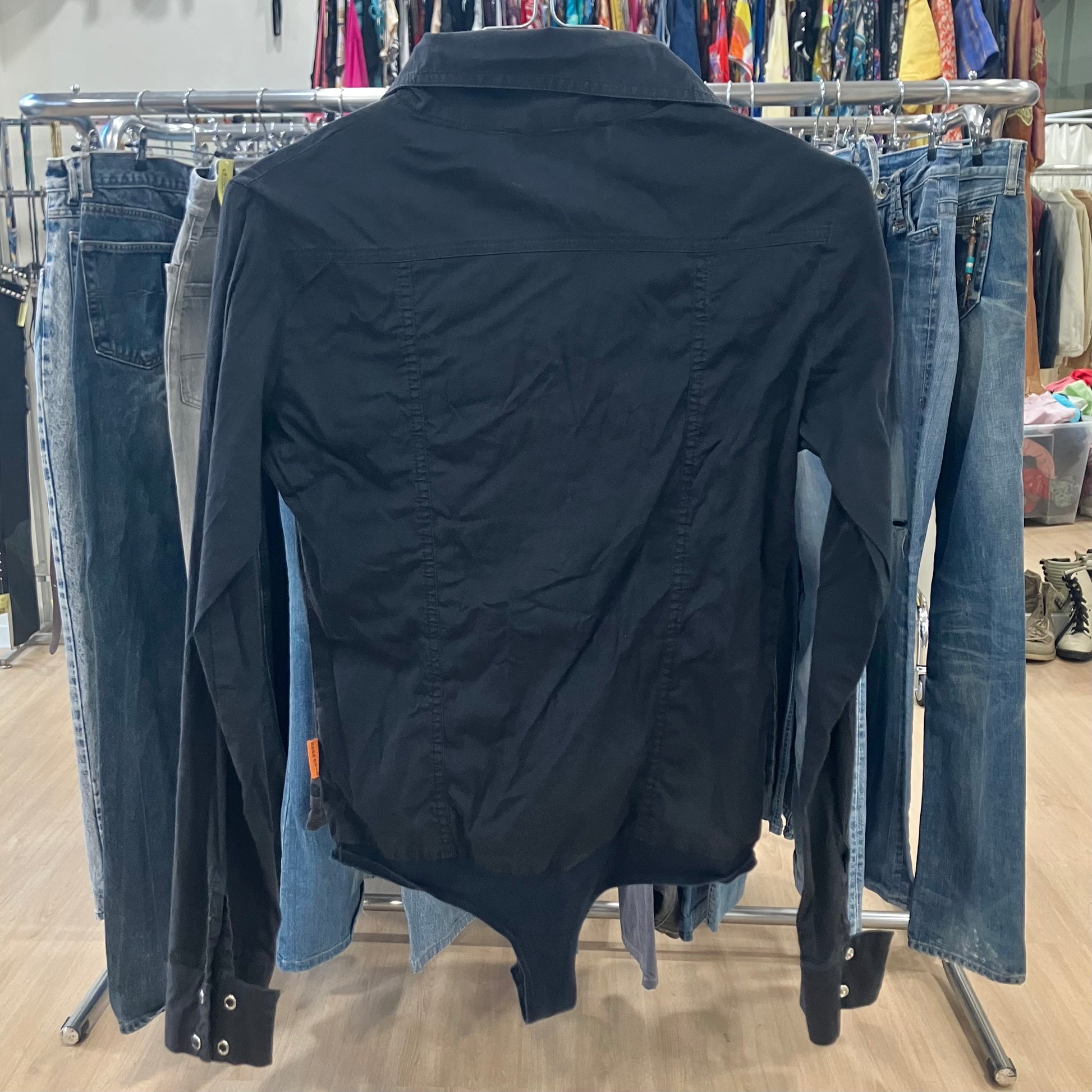 Black shirt on a rack with jeans in a store setting