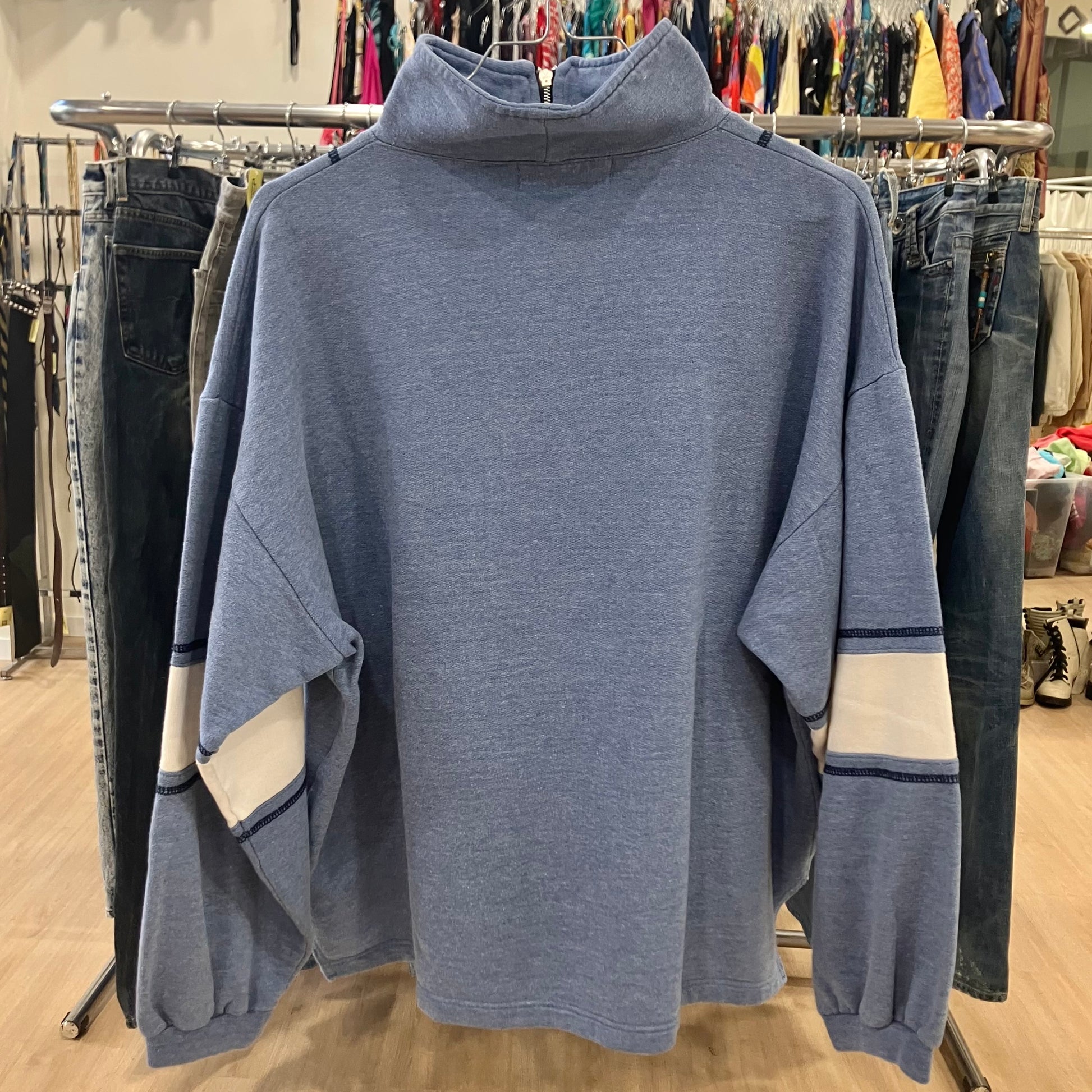 Blue sweater on a rack with clothing in the background