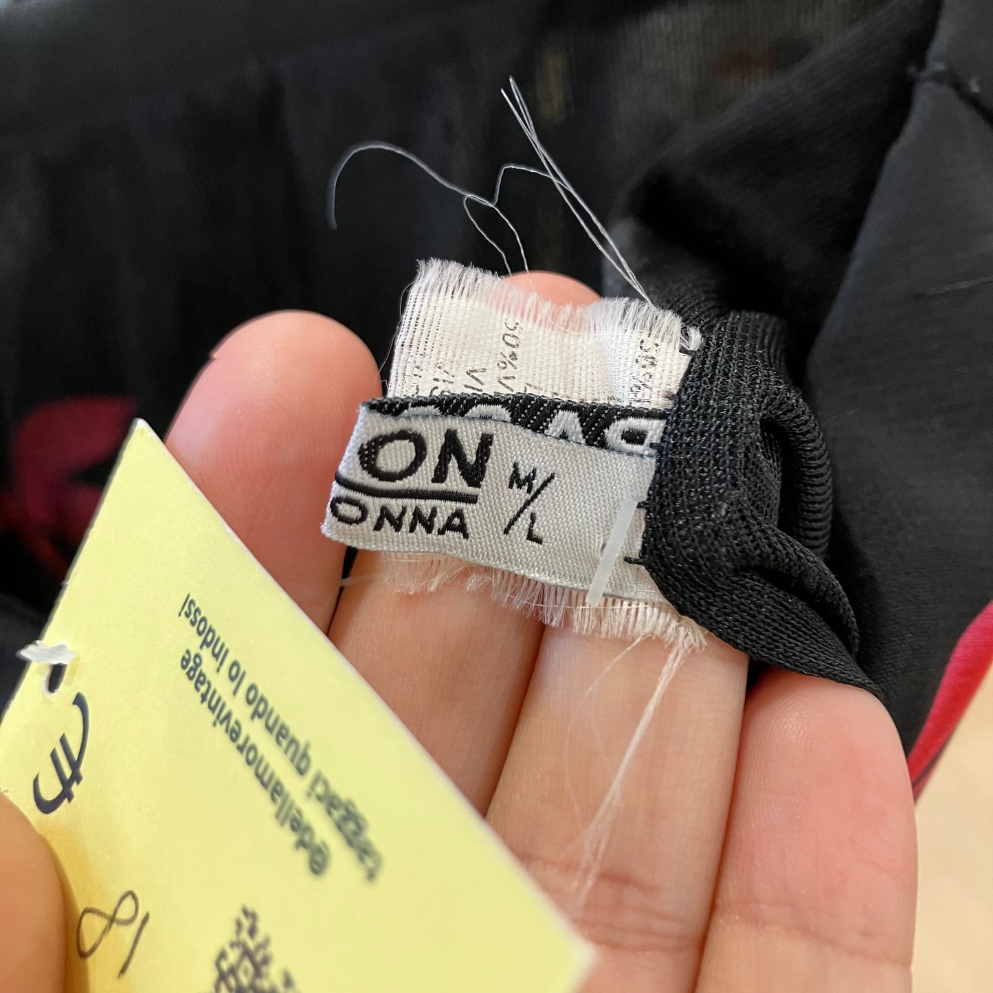 Close-up of a clothing tag held by a hand with a blurred background