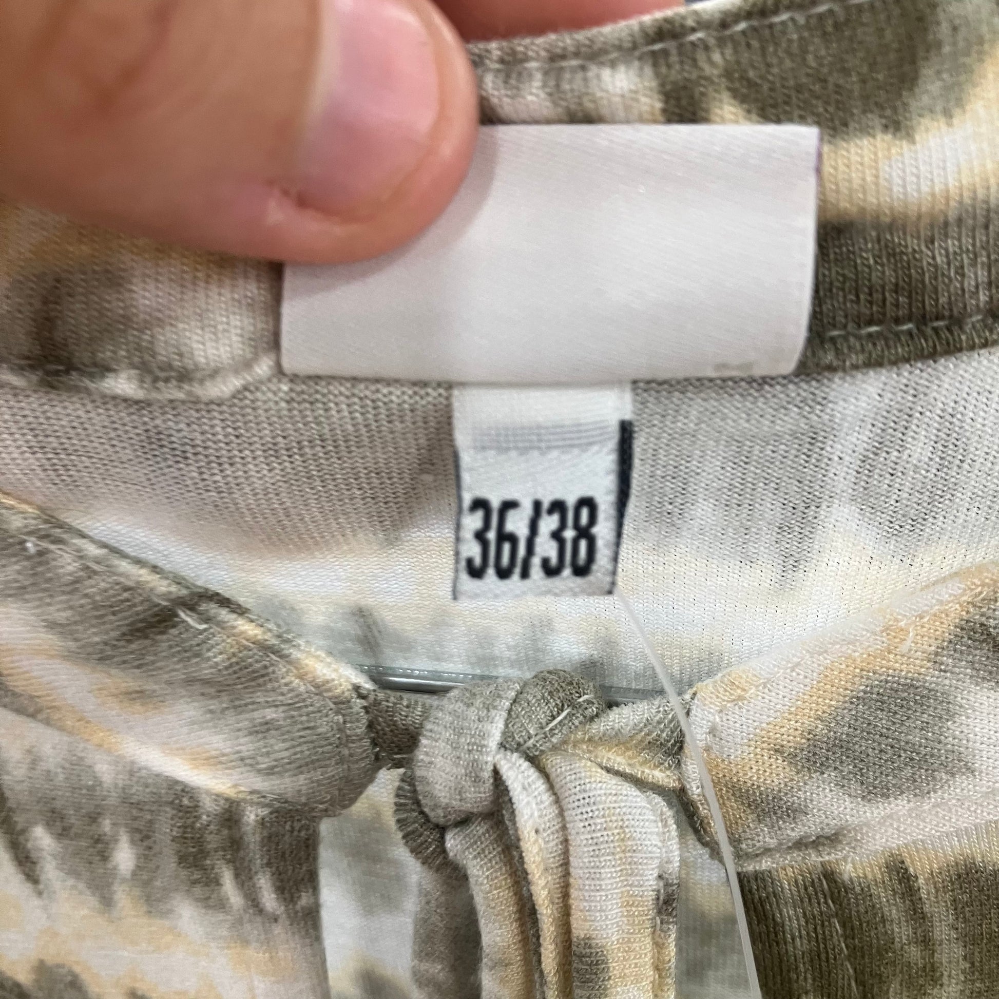 Camouflage-patterned fabric with a size tag displaying '36/38'
