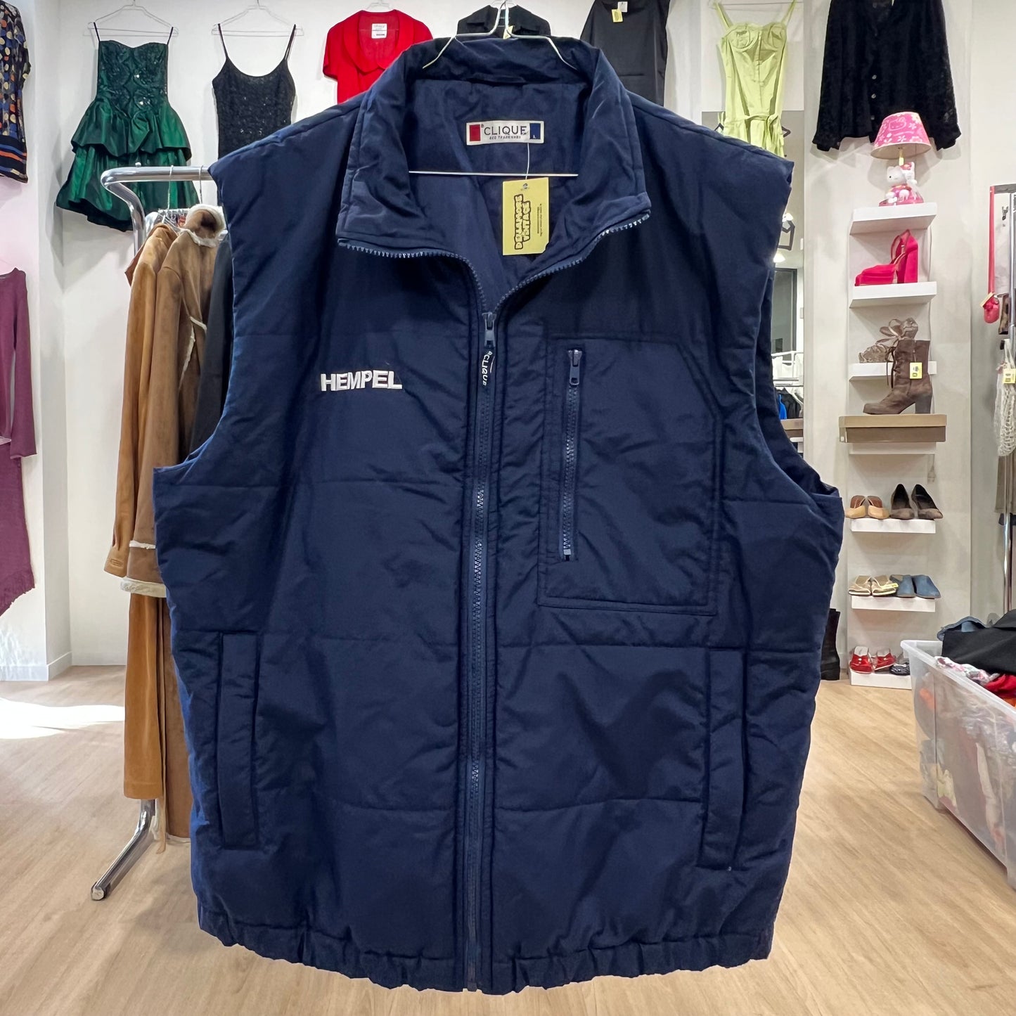Navy blue puffer vest with visible brand logo in a clothing store setting