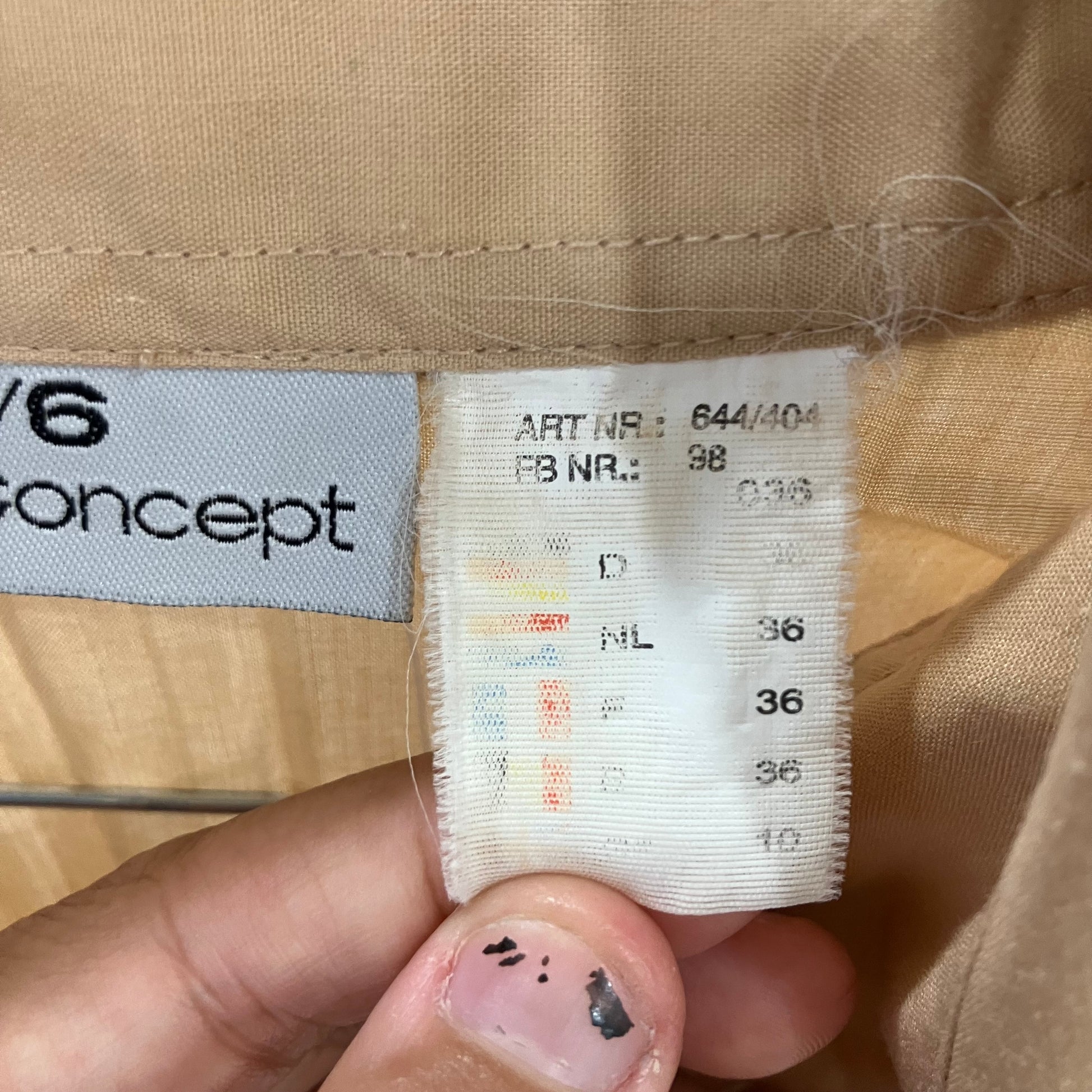 Close-up of a clothing tag with brand name and size information on beige fabric