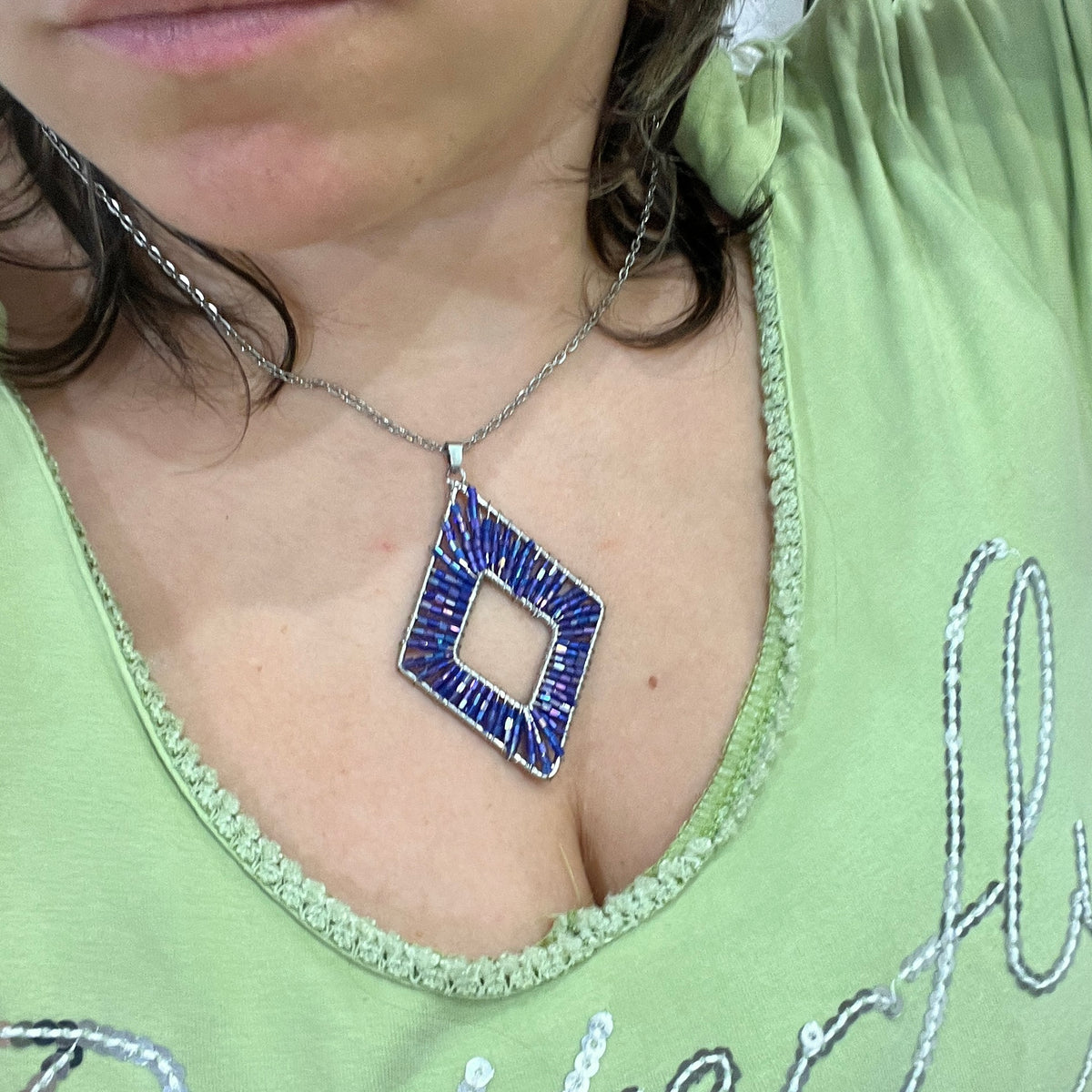 silver chain necklace with diamond shaped blue beaded pendant