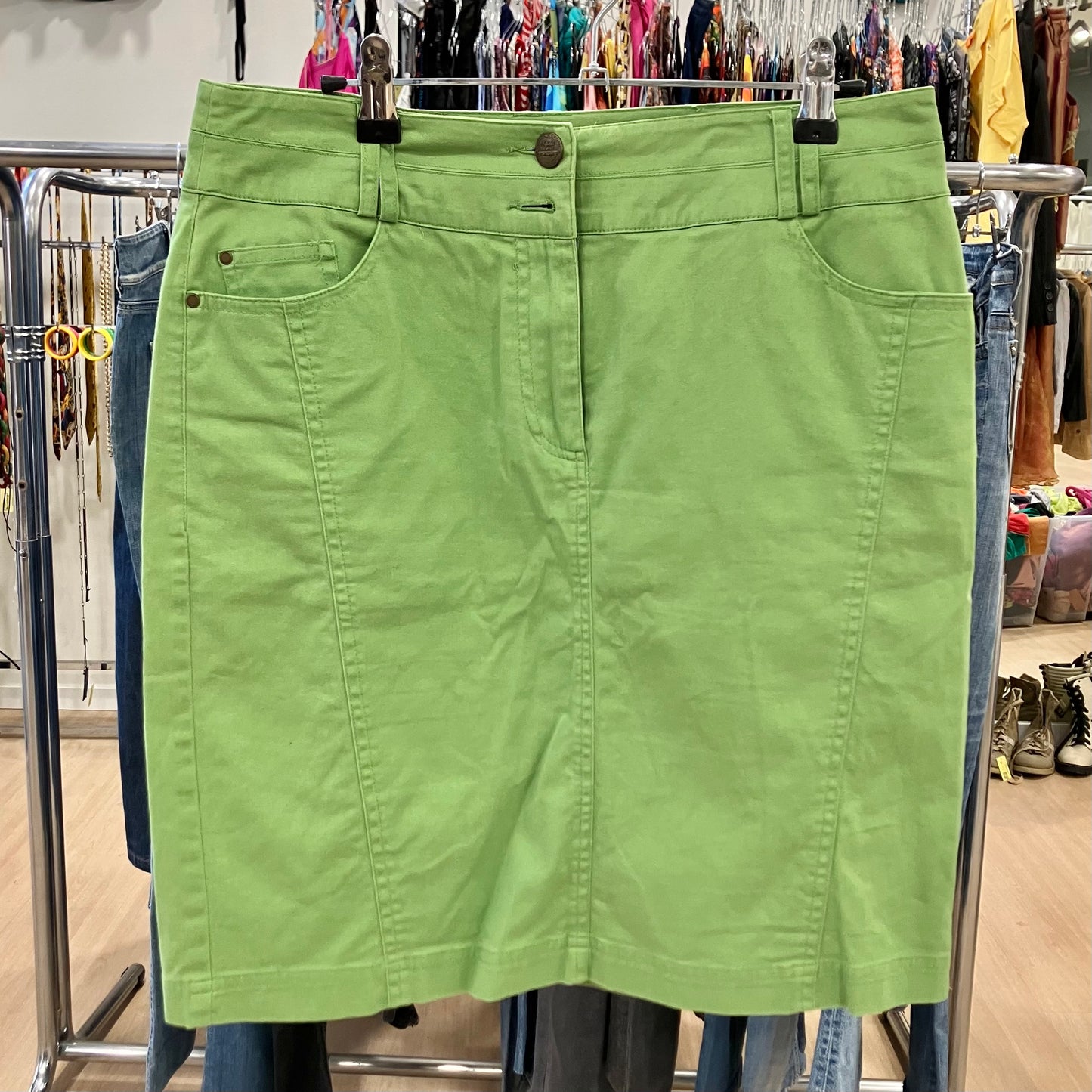 Green skirt hanging on a rack in a store setting