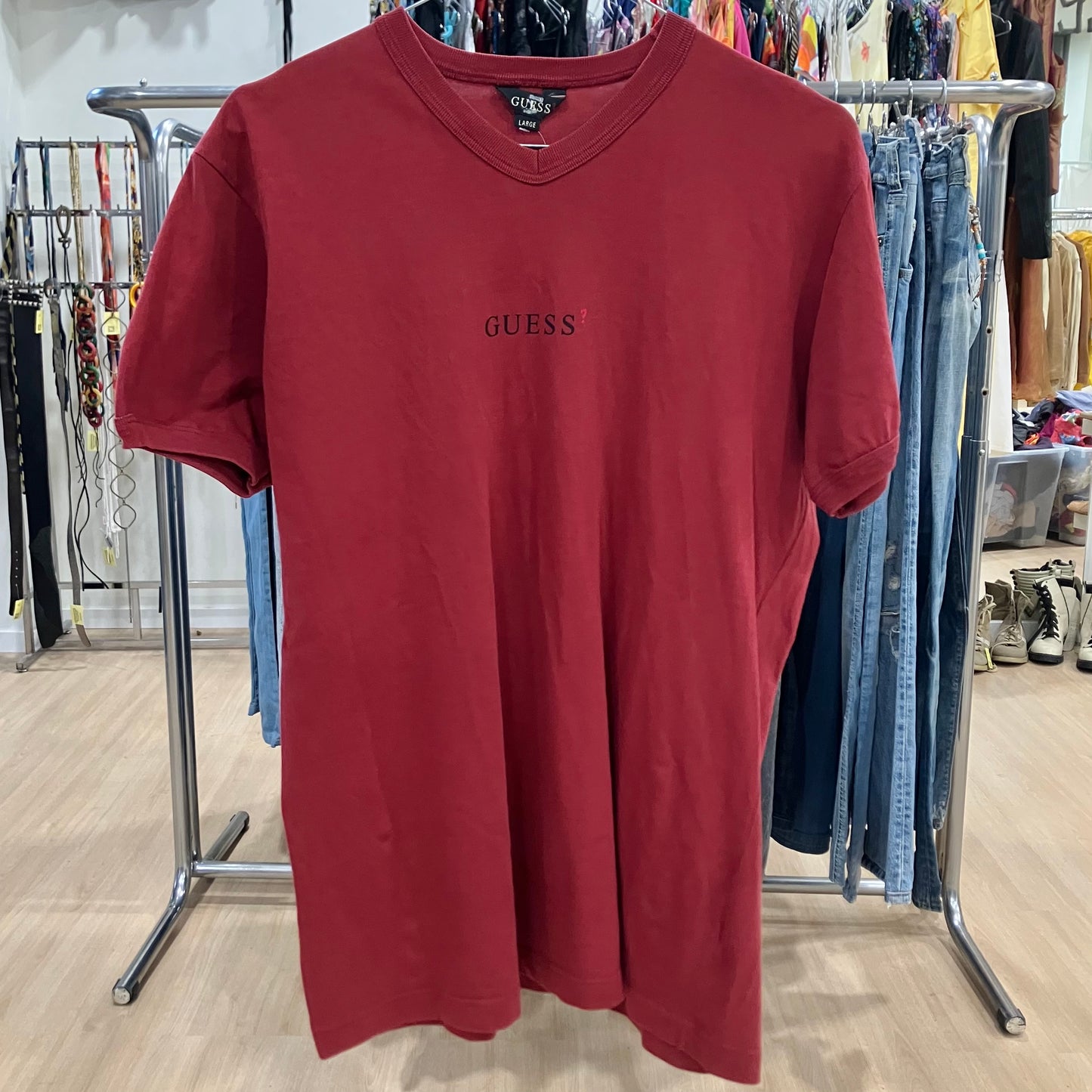 Red t-shirt with 'Guess' logo on a clothing rack in a store