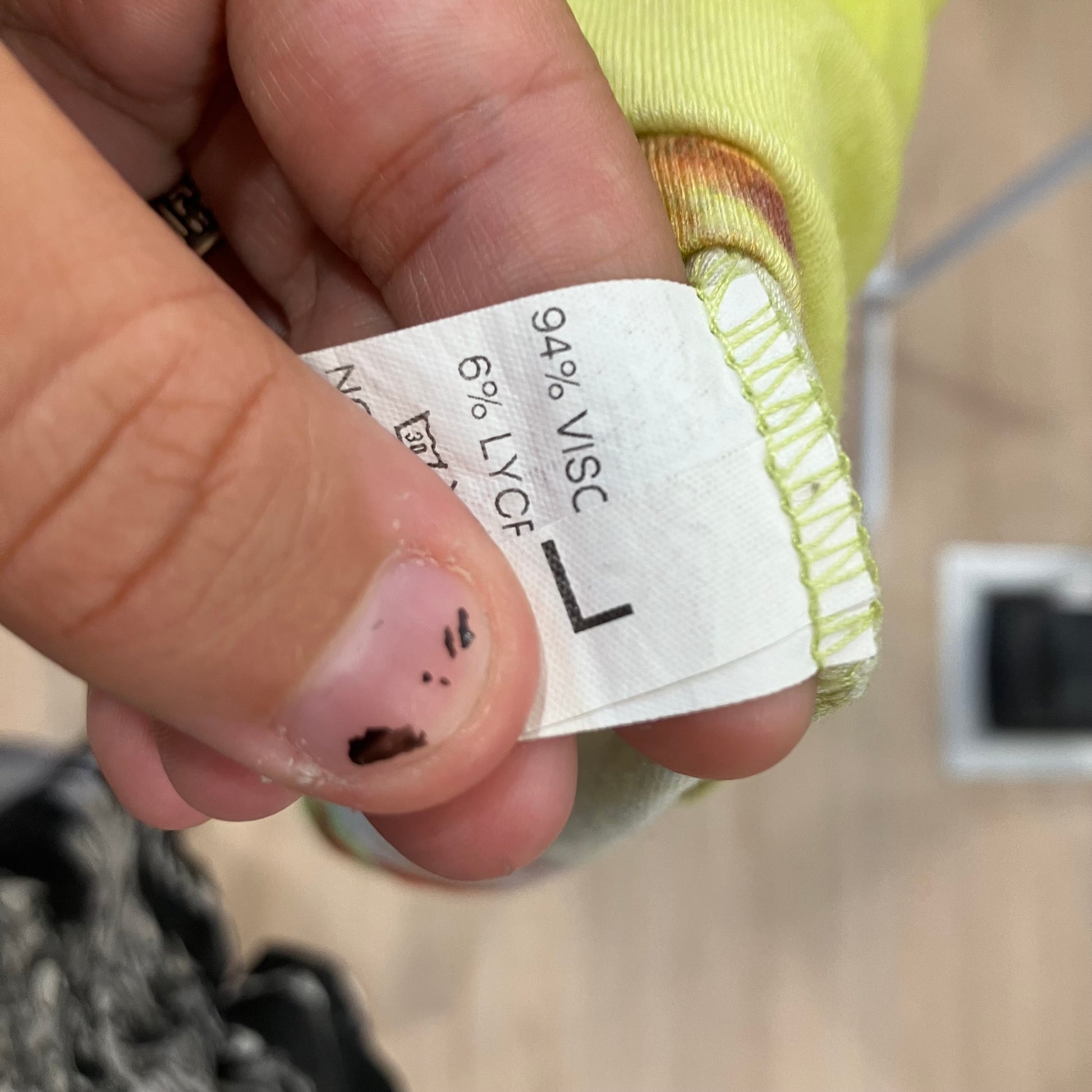 Close-up of a hand holding a fabric label with material information