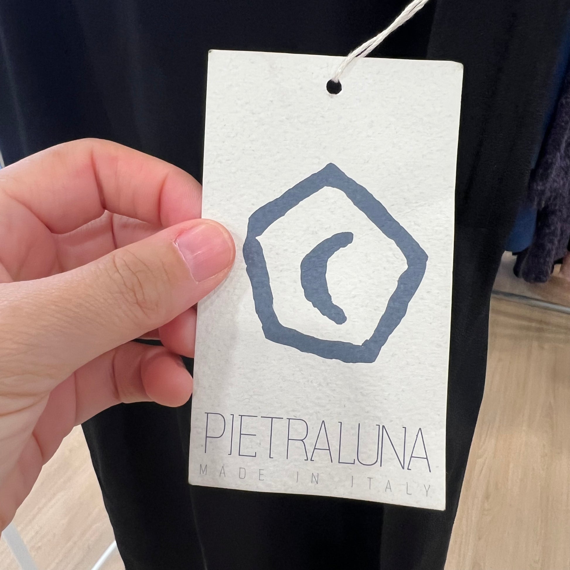 Hand holding a 'Pietraluna' brand tag with a logo