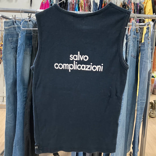 Black sleeveless shirt with 'salvo complicazioni' text hanging on a rack with jeans
