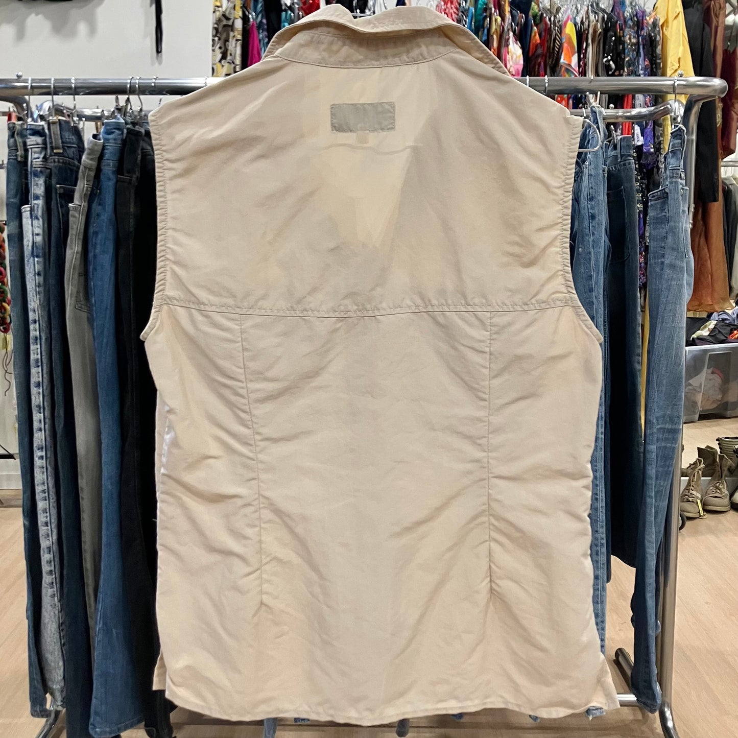 Beige vest on a rack with jeans in a store setting