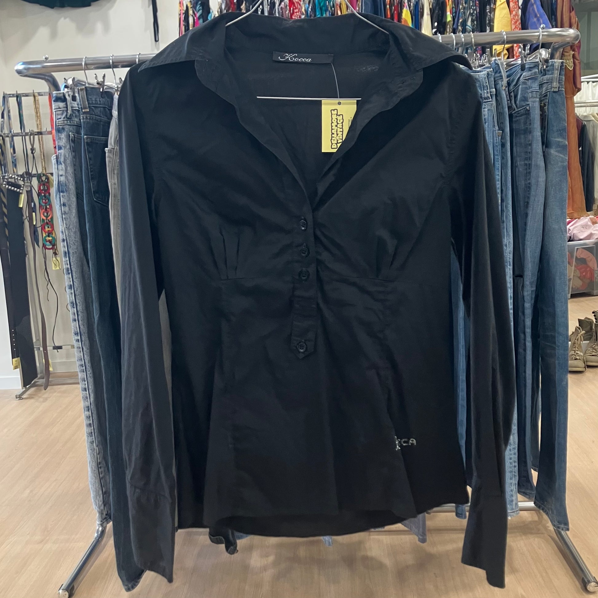 Black shirt on a rack with jeans in a store setting