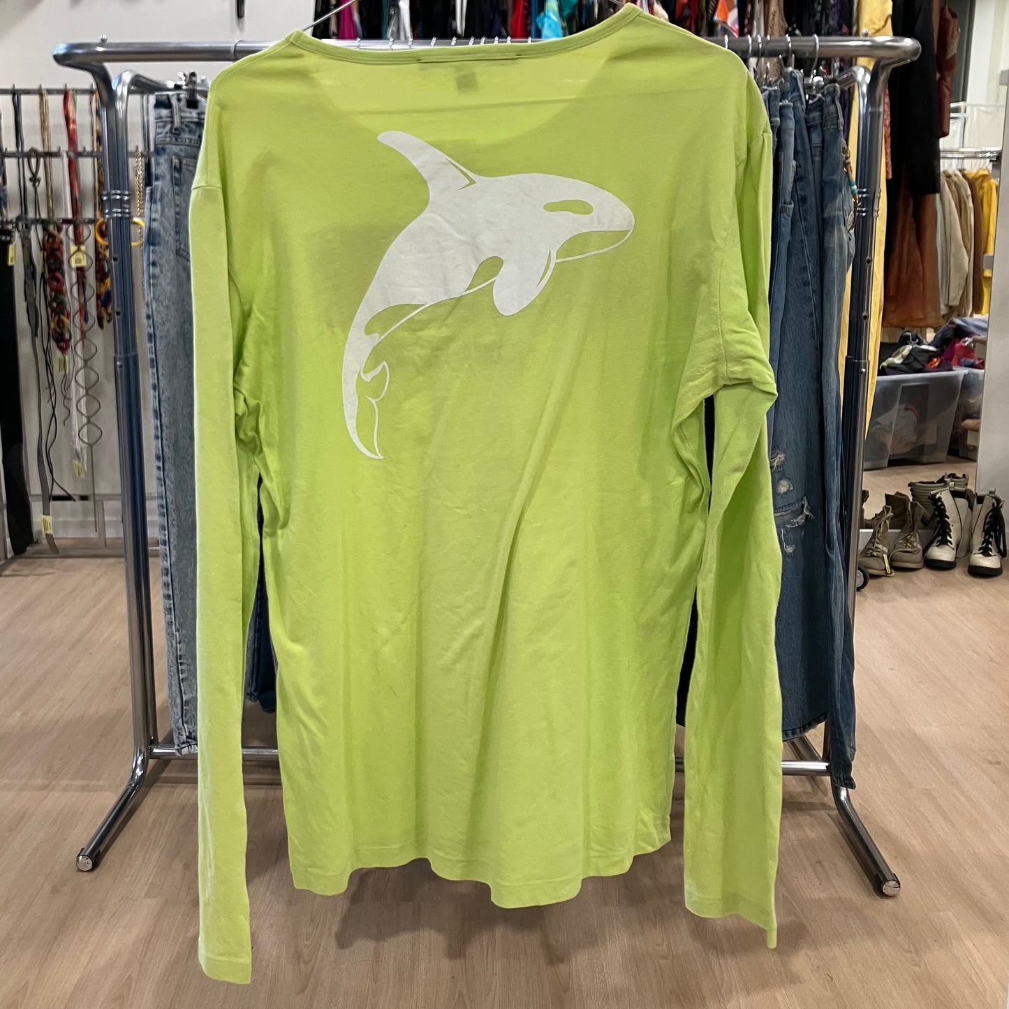Green long-sleeve shirt with a white graphic on a rack in a store