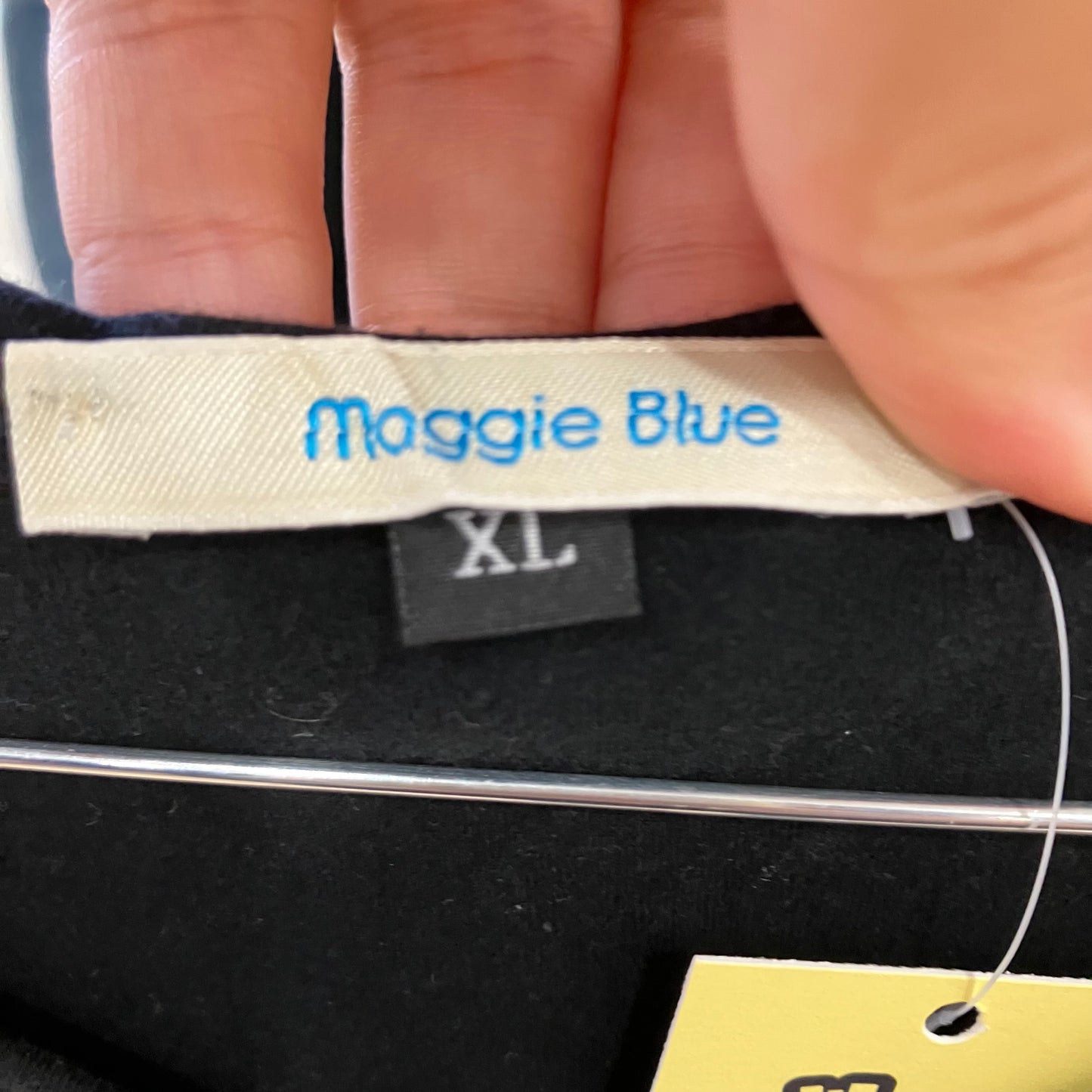 Maggie Blue size XL clothing label on black fabric, second hand fashion