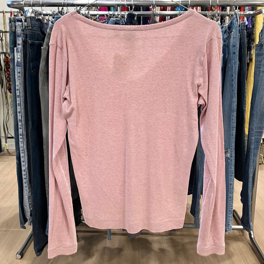 Pink long-sleeve shirt hanging on a rack with jeans in the background