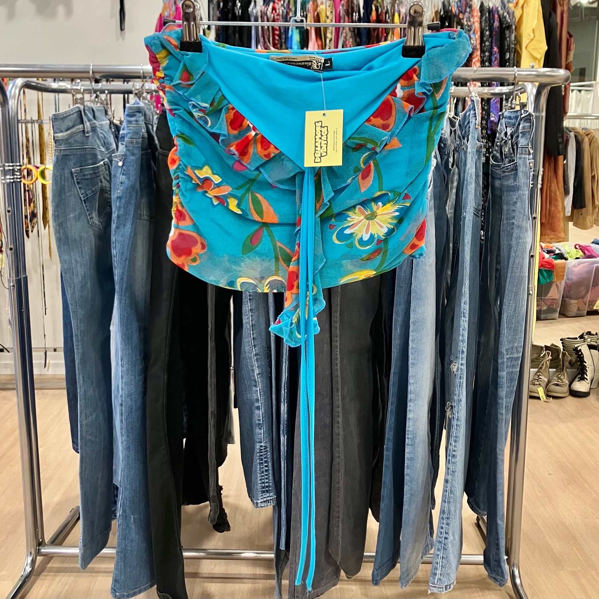 Blue floral off-shoulder blouse with ruffle detailing hanging on a rack inside a clothing store
