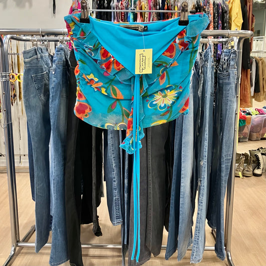 Blue floral off-shoulder blouse with ruffle detailing hanging on a rack inside a clothing store