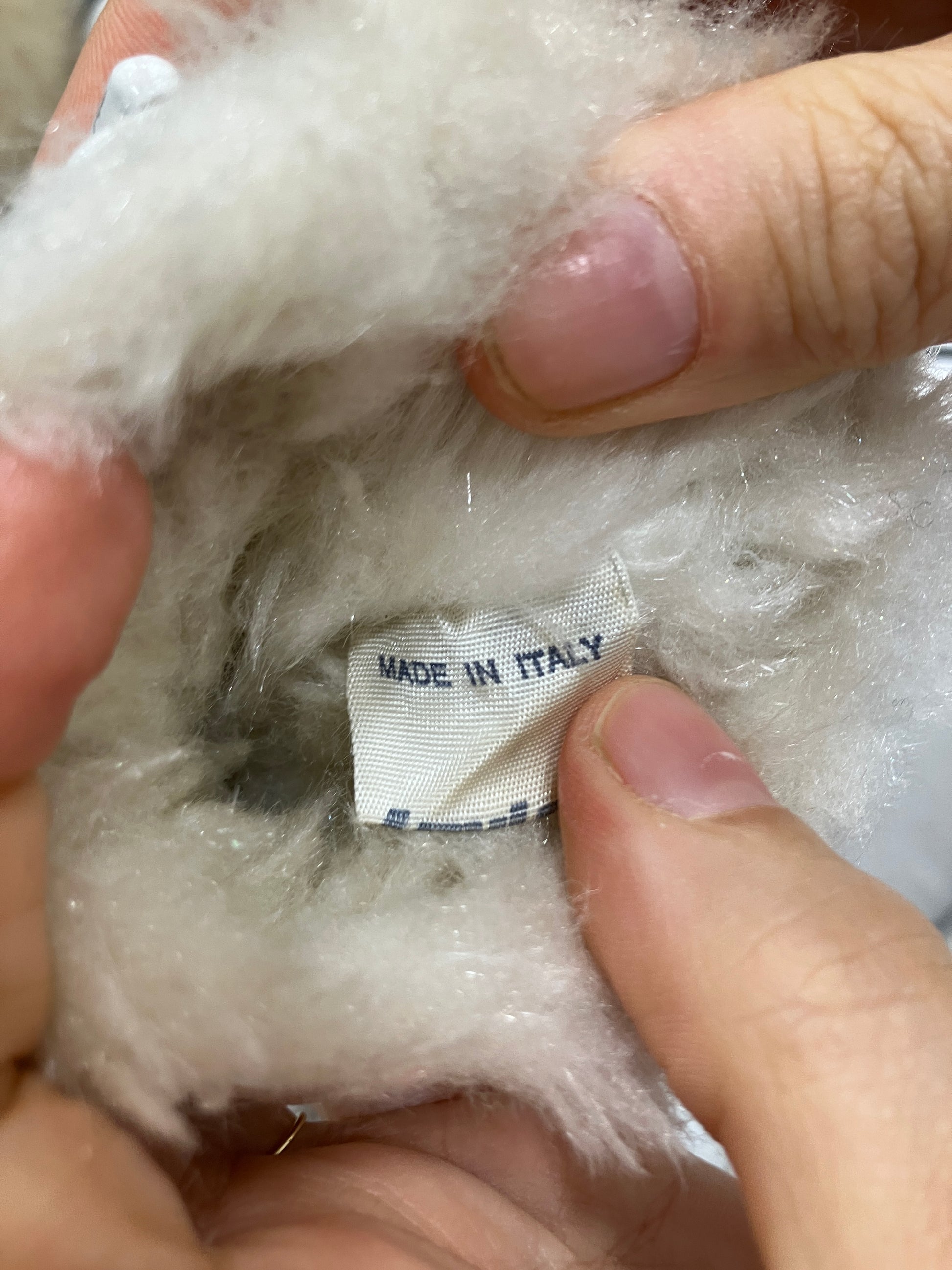 Close-up of a label on a product with hands holding it, showing 'Made in Italy'