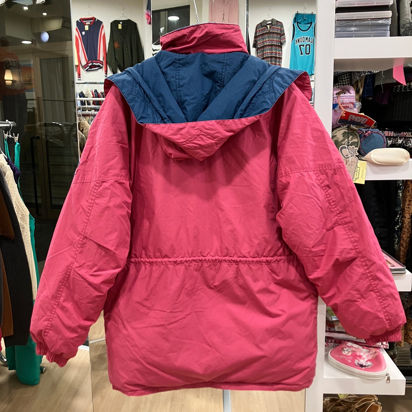 Pink jacket with blue hood in a store setting
