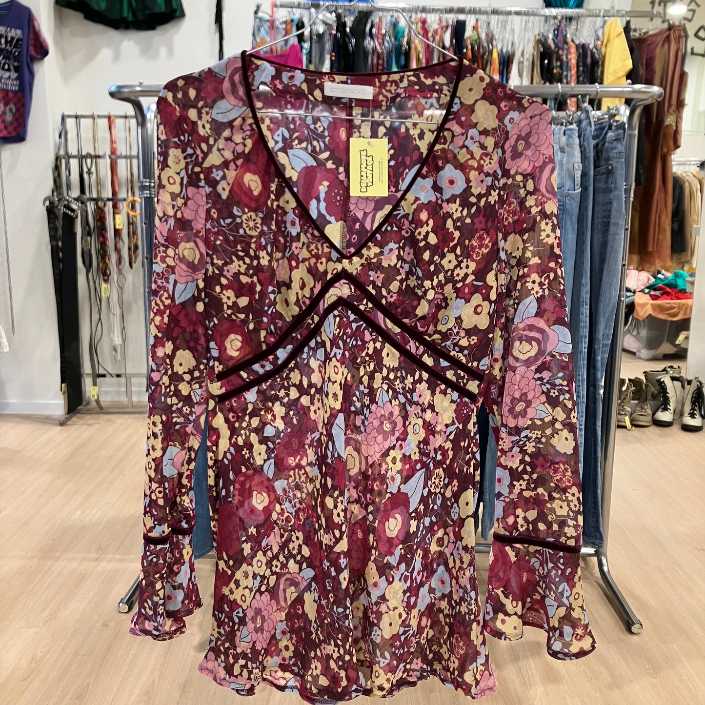 Sheer floral long-sleeve blouse with a V-neck hanging on a rack inside a clothing store