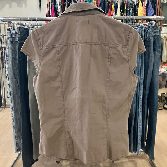 Beige sleeveless shirt on a rack with jeans in a store setting