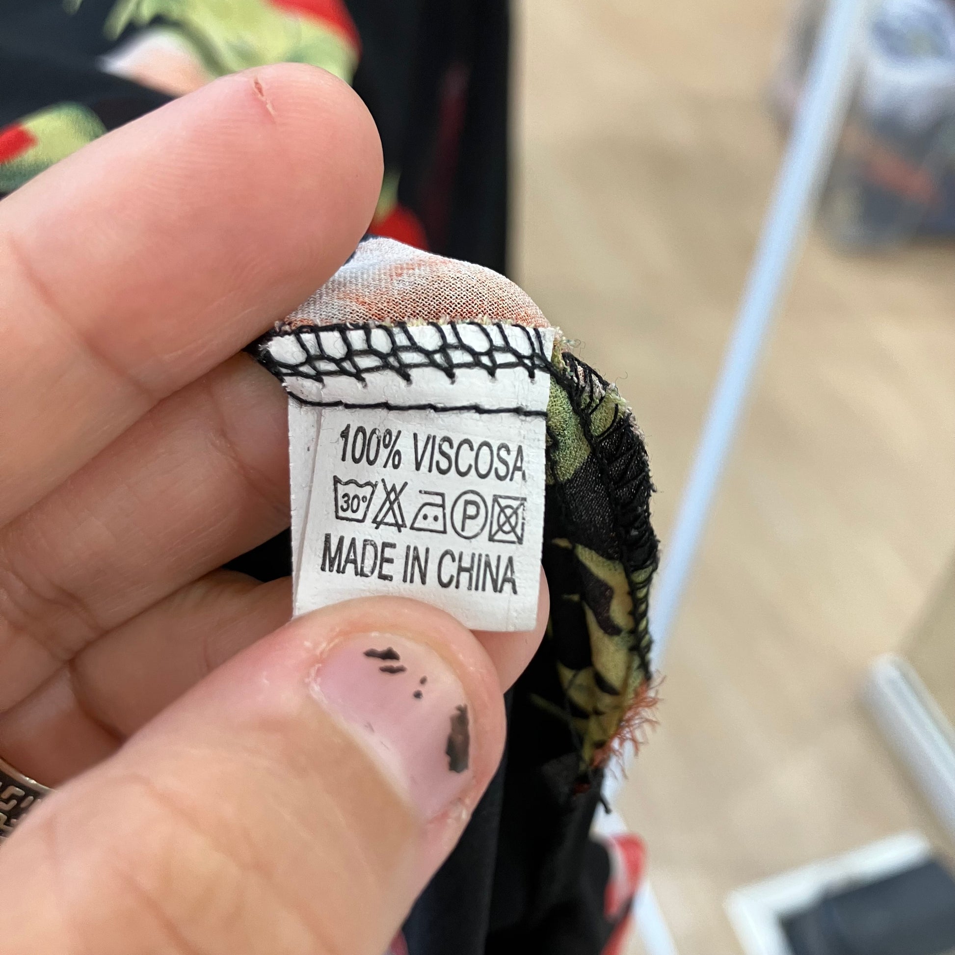 Hand holding a fabric tag with washing instructions and 'Made in China' text