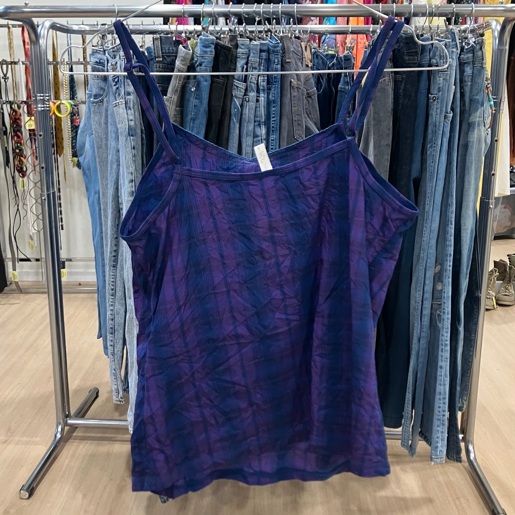 Blue tank top hanging on a rack with jeans in a store setting