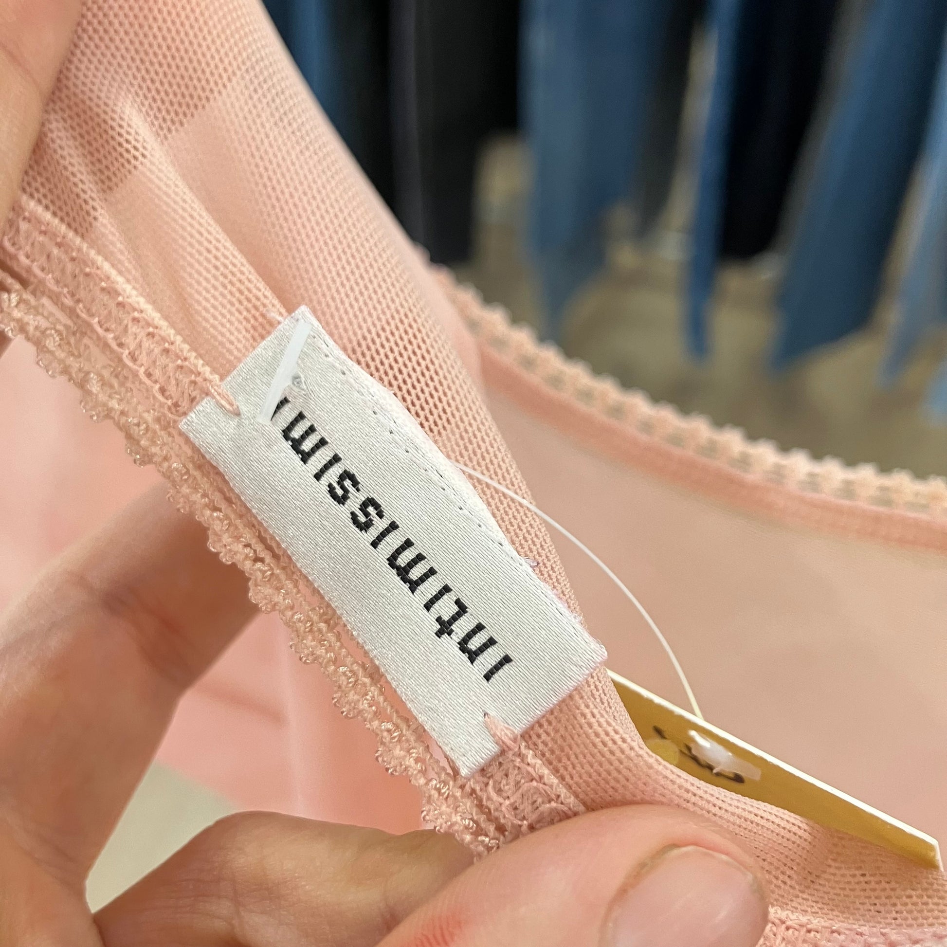 Close-up of hand holding pink lace mesh garment with Intimissimi label