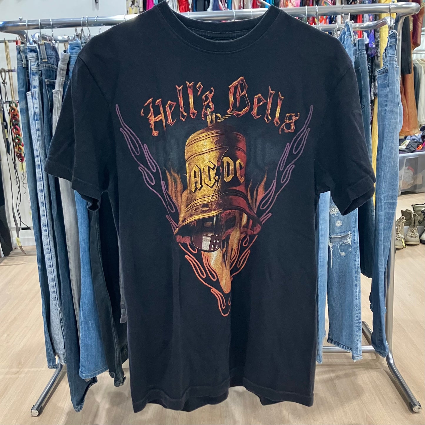 Black t-shirt with AC/DC graphic design hanging on a rack with jeans