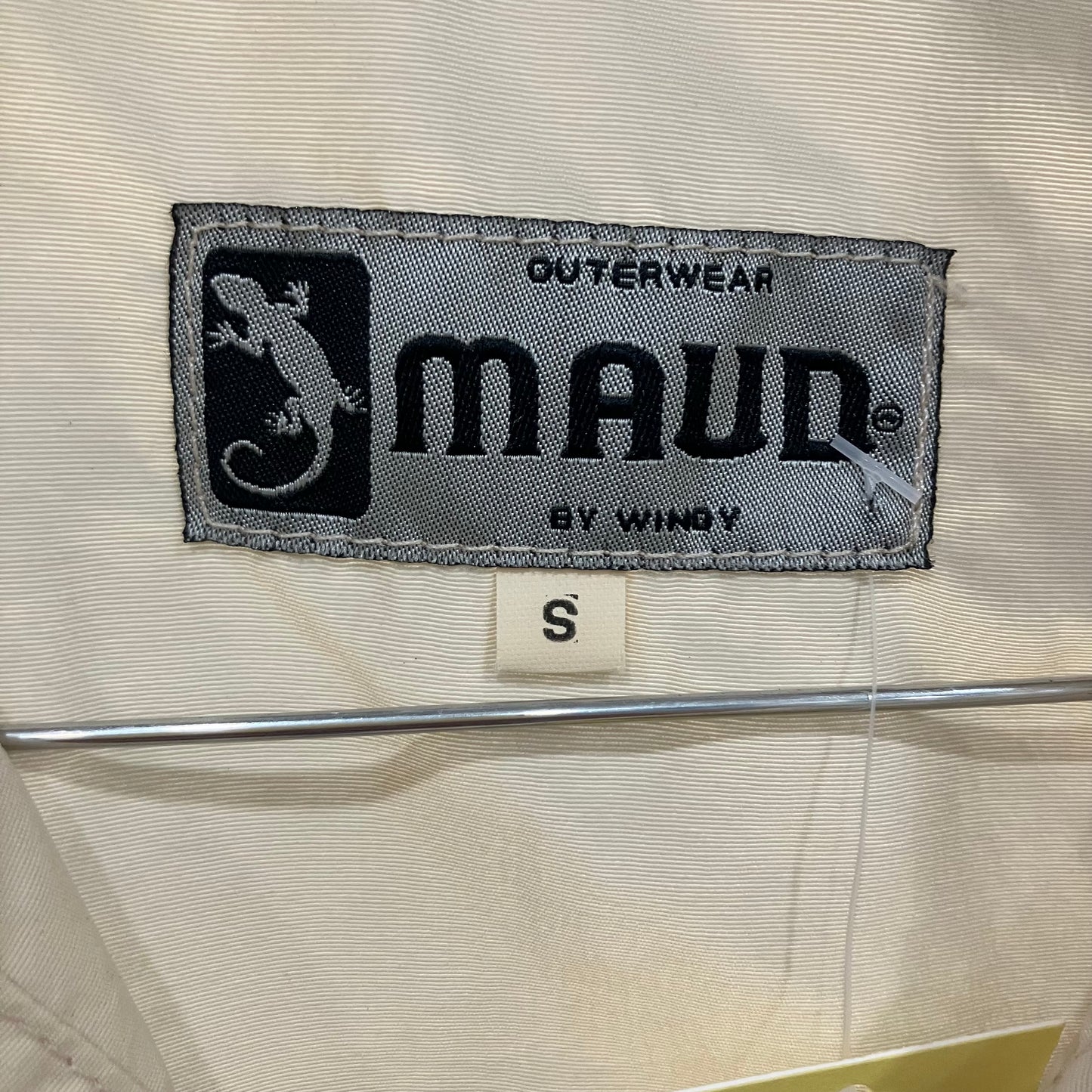 Maud by Wingy label on a beige jacket with a lizard logo