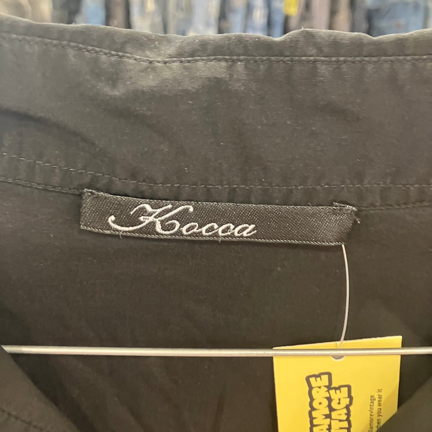 Dark gray shirt with a 'Kocca' label and a yellow tag in the background