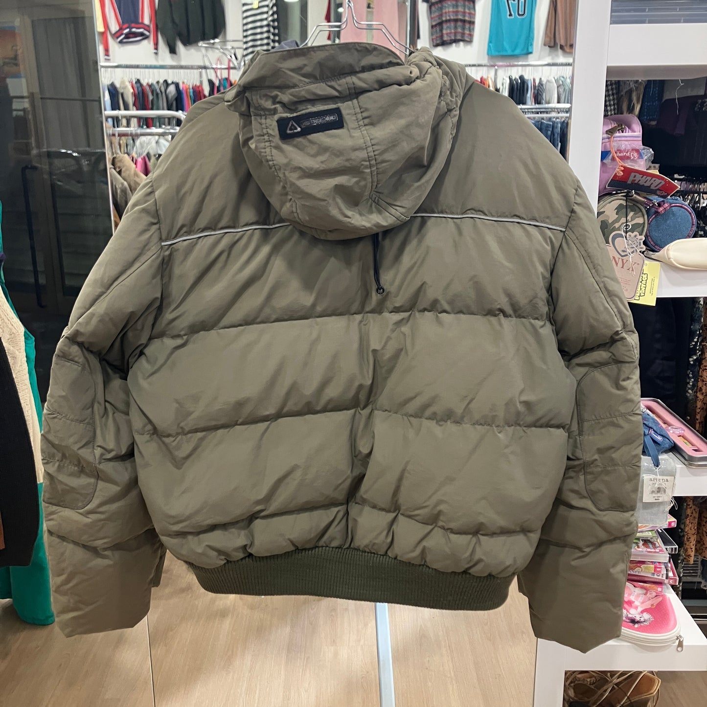 Green puffer jacket with a brand logo on a mannequin in a store setting