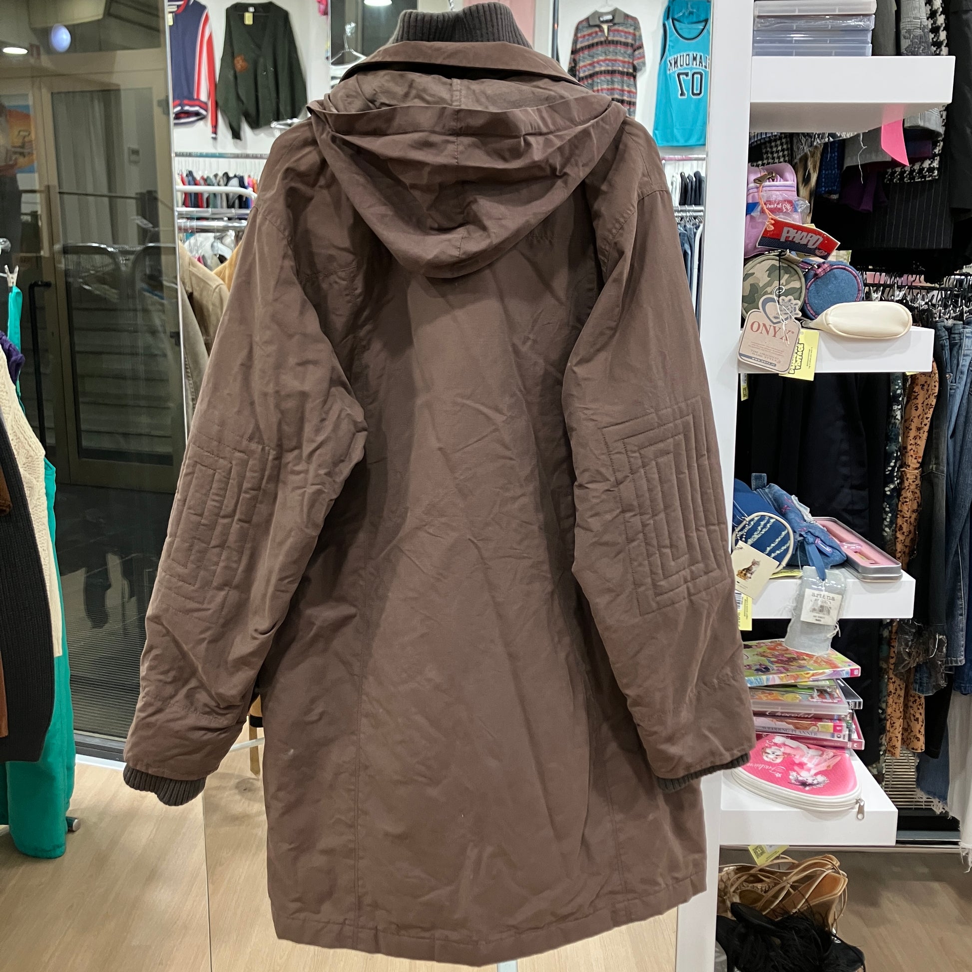 Brown parka jacket displayed in a store setting with various items in the background