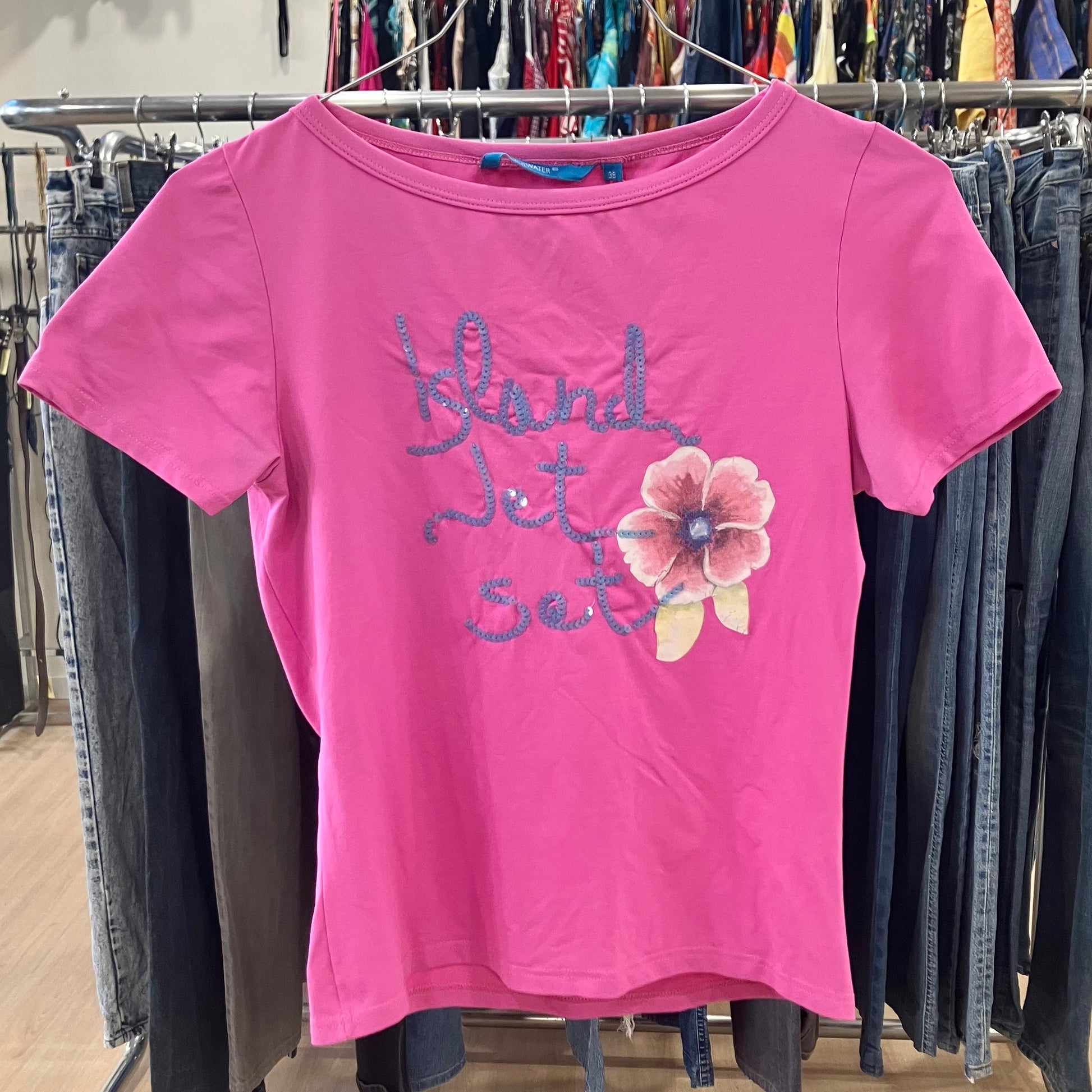 Pink t-shirt with floral design and text on a rack of clothes