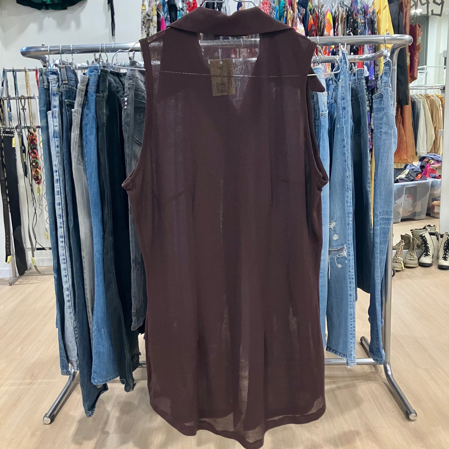 Brown sleeveless dress on a rack with jeans in a store setting